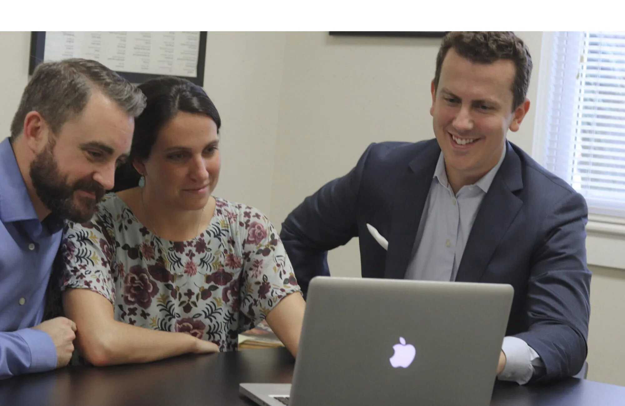 Justin Luther smiling with a couple as they review a financial plan on a laptop